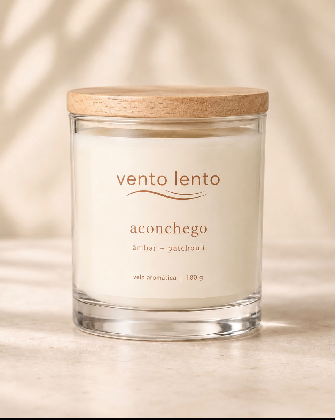 Vela Aconchego Âmbar e Patchouli em copo de vidro transparente com tampa de madeira clara